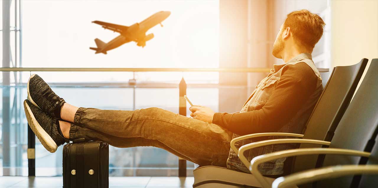 hombre en aeropuerto con los pies en maletas