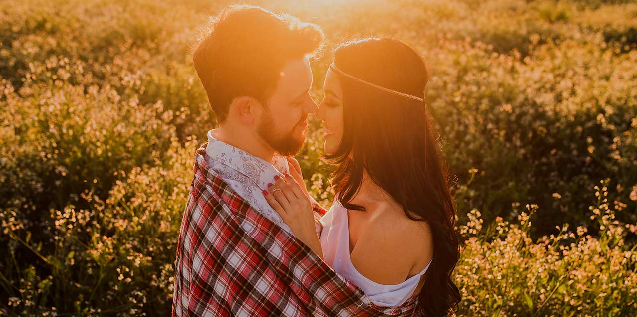 Pareja besándose en prado con flores Pareja besándose en prado con flores