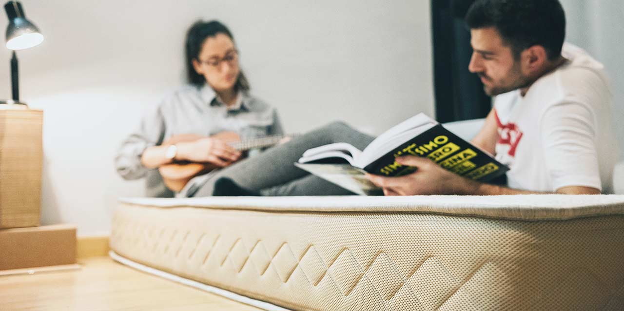 pareja tumbada en colchón con ukelele y revista