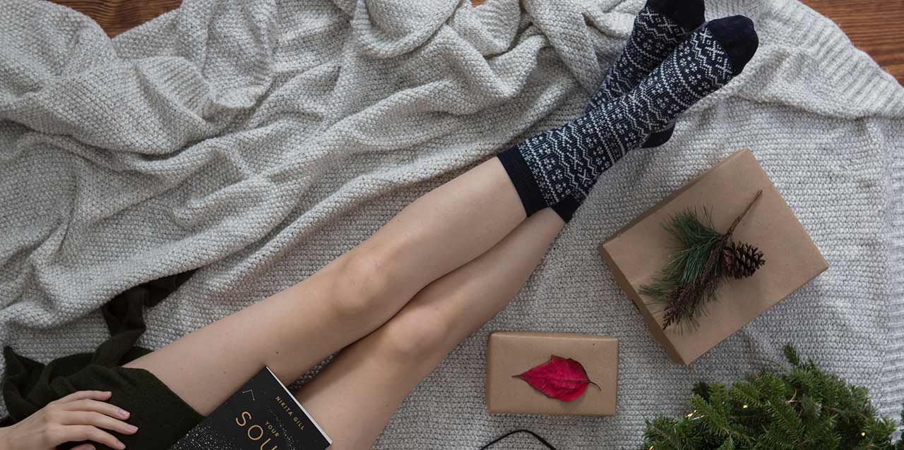 chica sentada en manta con calcetines con estampado navideño