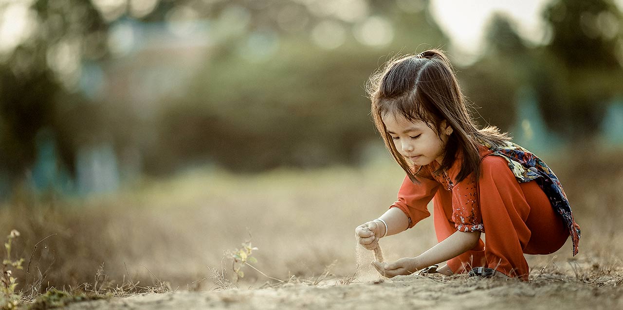 niña jugando con tierra agachada