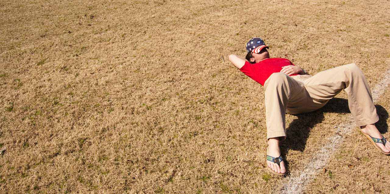 hombre durmiendo junto a línea de campo de fútbol