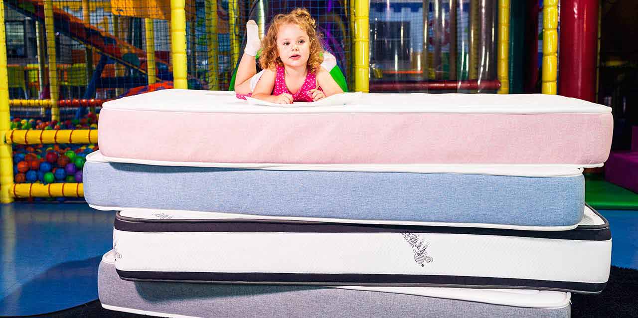 niña tumbada encima de colchones para niños
