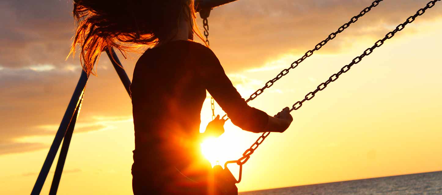 niña columpiándose en atardecer niña columpiándose en atardecer