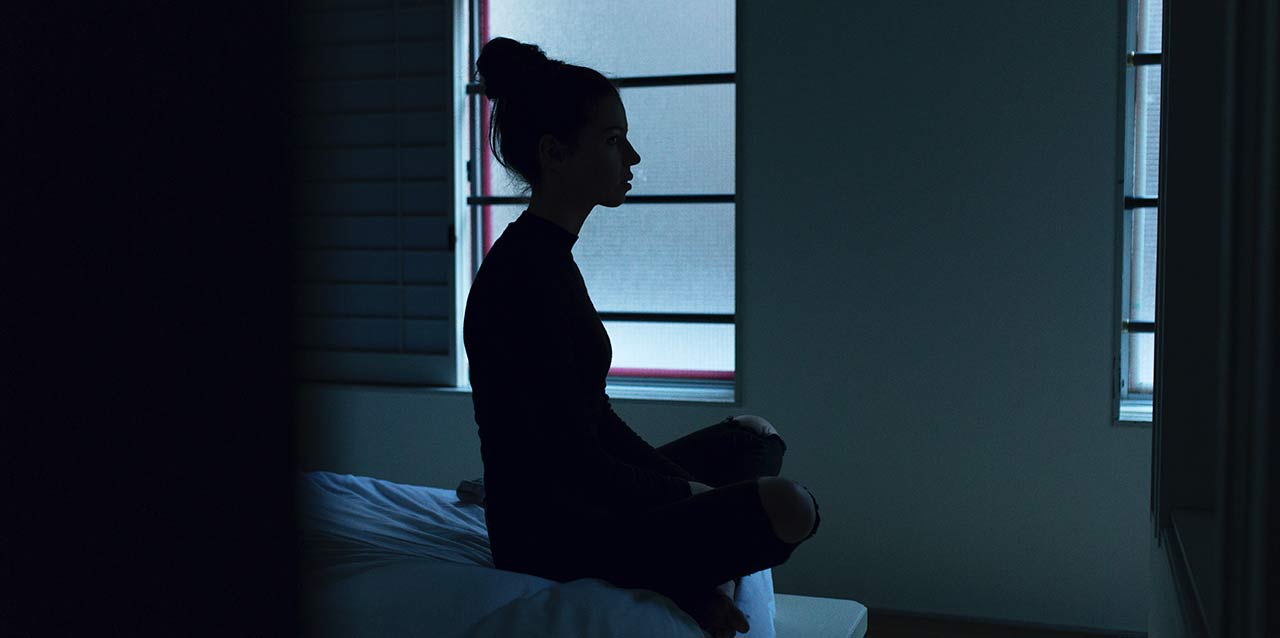 chica sentada en el pico de la cama