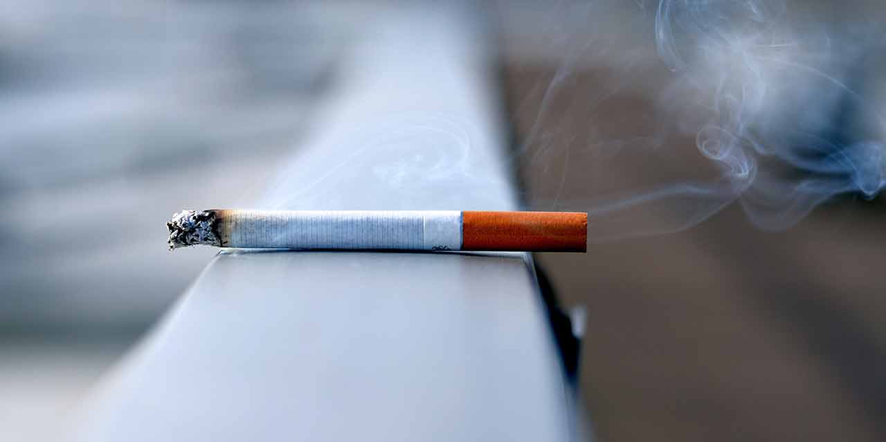 dia-mundial-sin-el-tabaco cigarro encendido en barandilla
