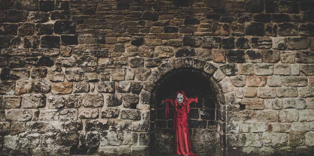 calavera con vestido rojo en muro de rocas