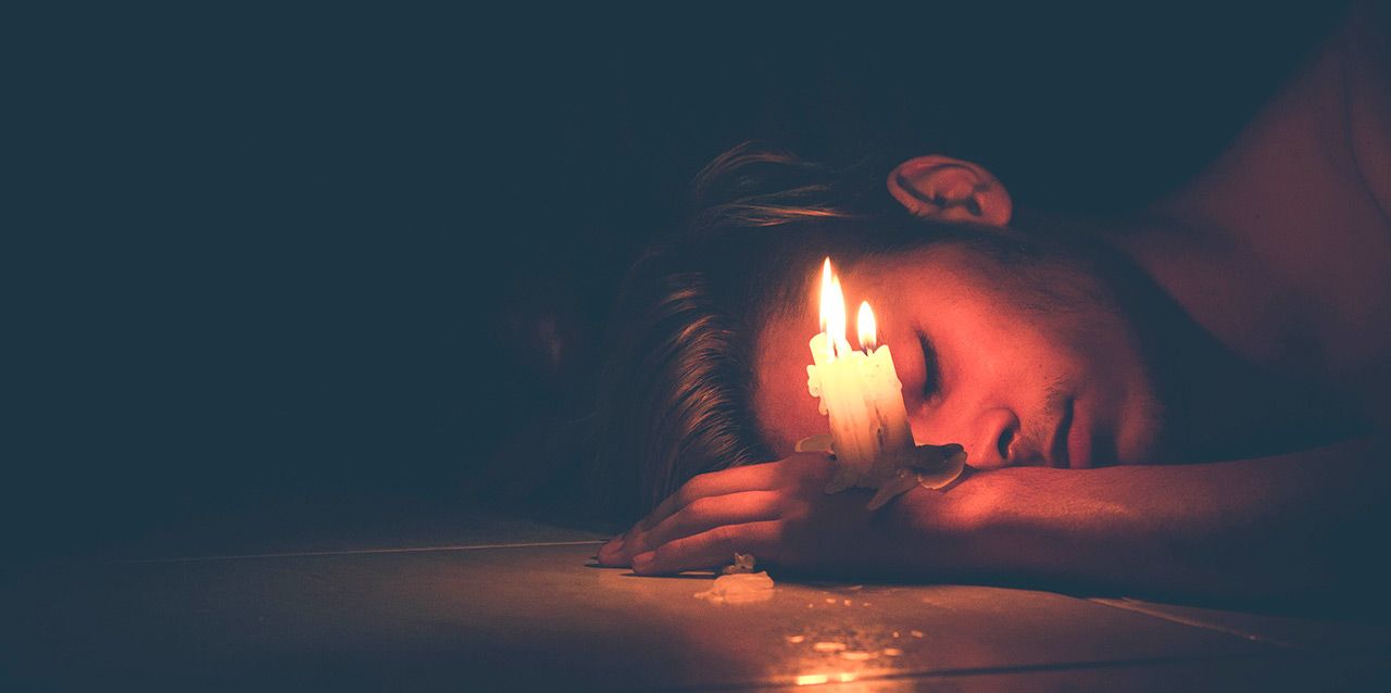 chico durmiendo con velas en la mano