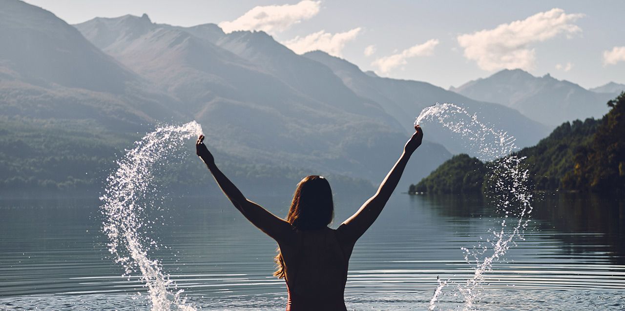 mujer jugando con agua en lago