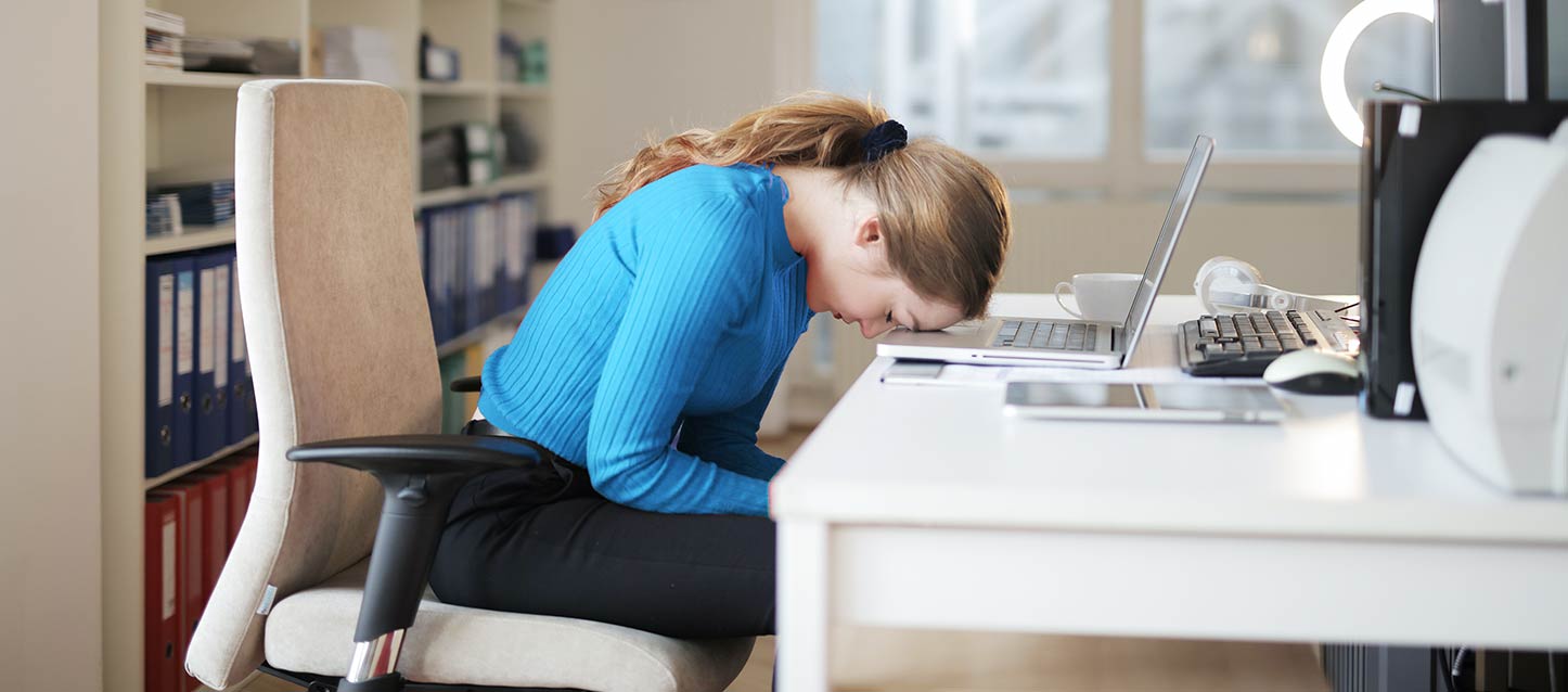Cómo afecta la deficiencia del sueño en el rendimiento académico estudiante con deficiencia de sueño durmiendo en su escritorio con la cabeza apoyada en su ordenador portatil