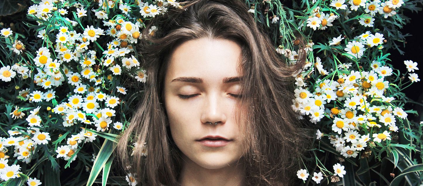 Hipnosis para dormir chica de pelo largo moreno con los ojos cerrados y septum en la campo rodeada de margaritas
