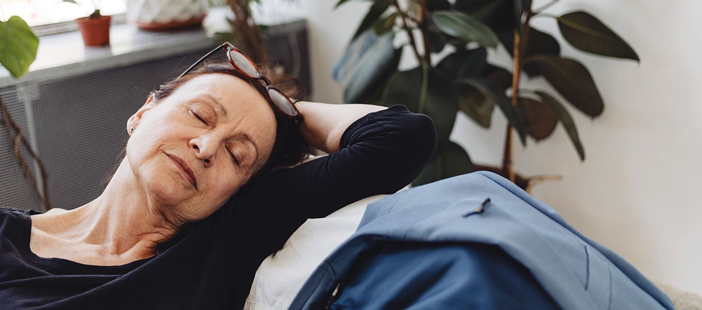 Apnea del sueño en la tercera edad mujer con gafas en el pelo con jersei negro durmiendo en un sofá
