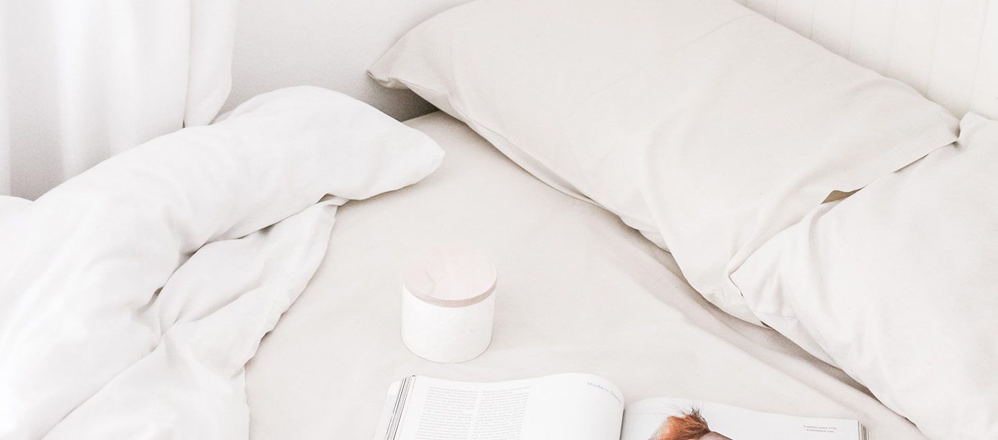 cama con almohadas de latex, edredon y un libro