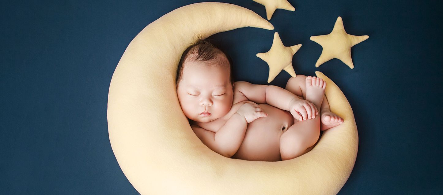 Es normal que un bebé ronque al dormir bebe dormido dentro de un cojin con forma de luna y estrellas