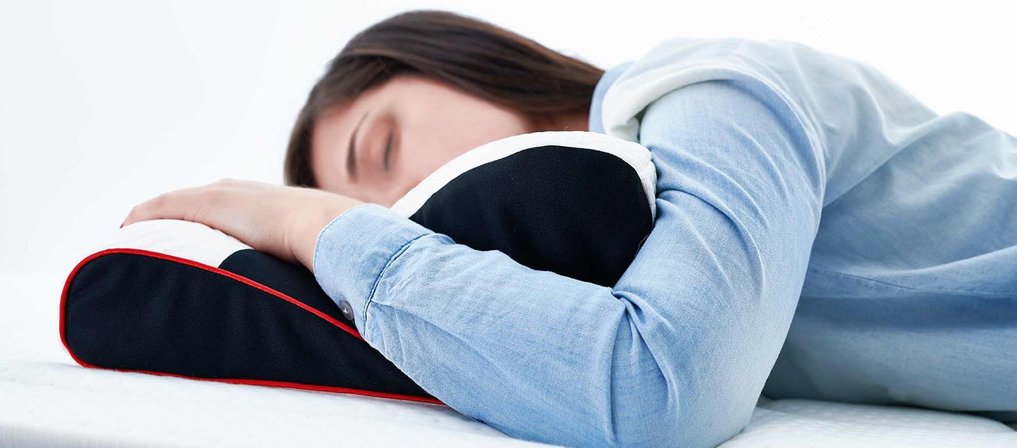 chica con dolor cervical durmiendo boca abajo con una almohada cervical viscoelastica en la que apoya su brazo