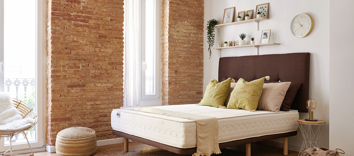 habitación con cama, mesita con lampara, estanterías con marcos y varias ideas para decorar encima del cabecero de cama