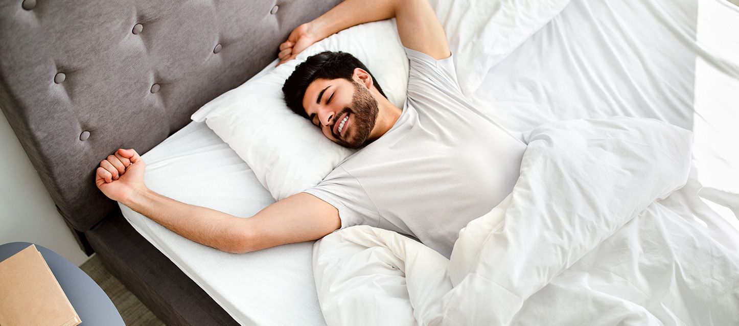 chico moreno con barba durmiendo boca arriba en la cama