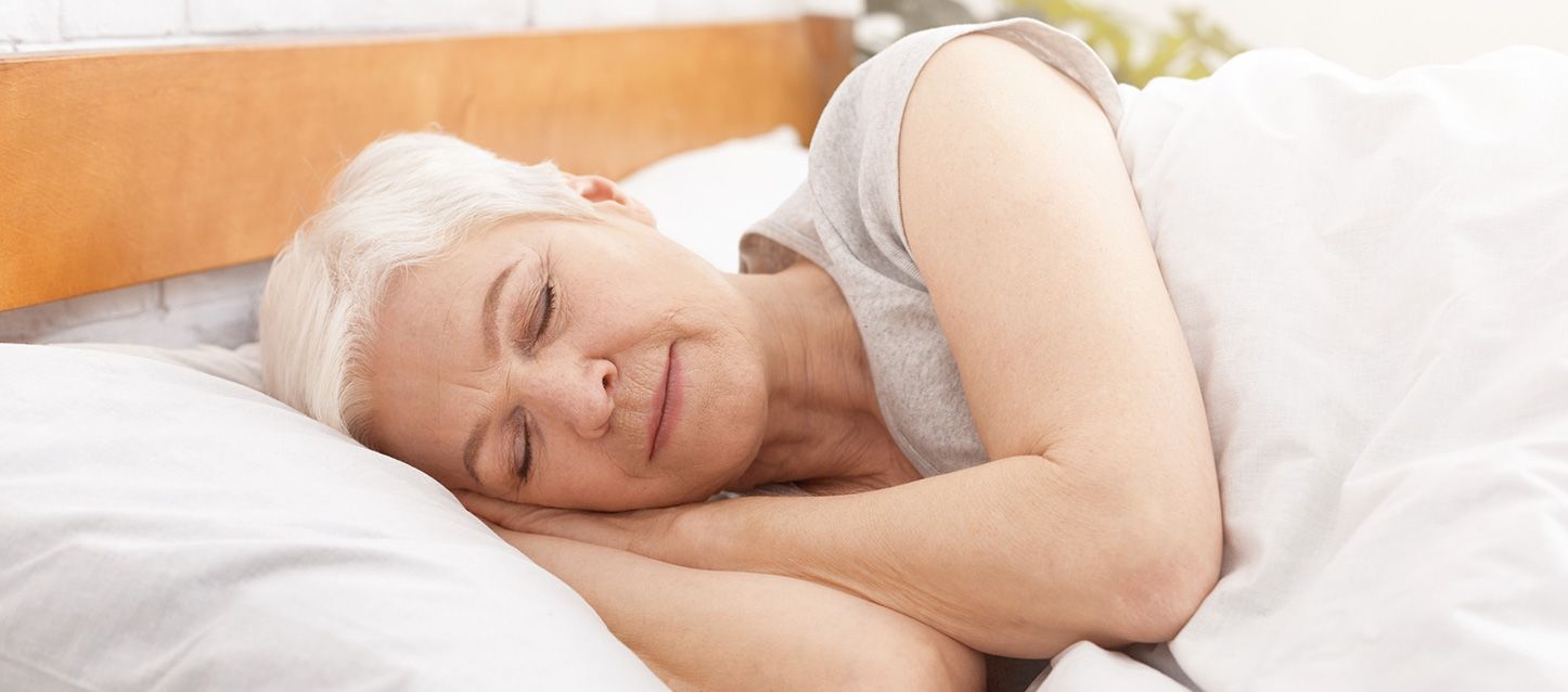 mujer de pelo blanco durmiendo de lado en la cama