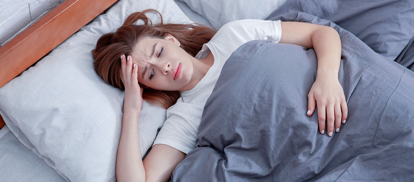 chica de pelo largo castaño metida en la cama con problemas para dormir