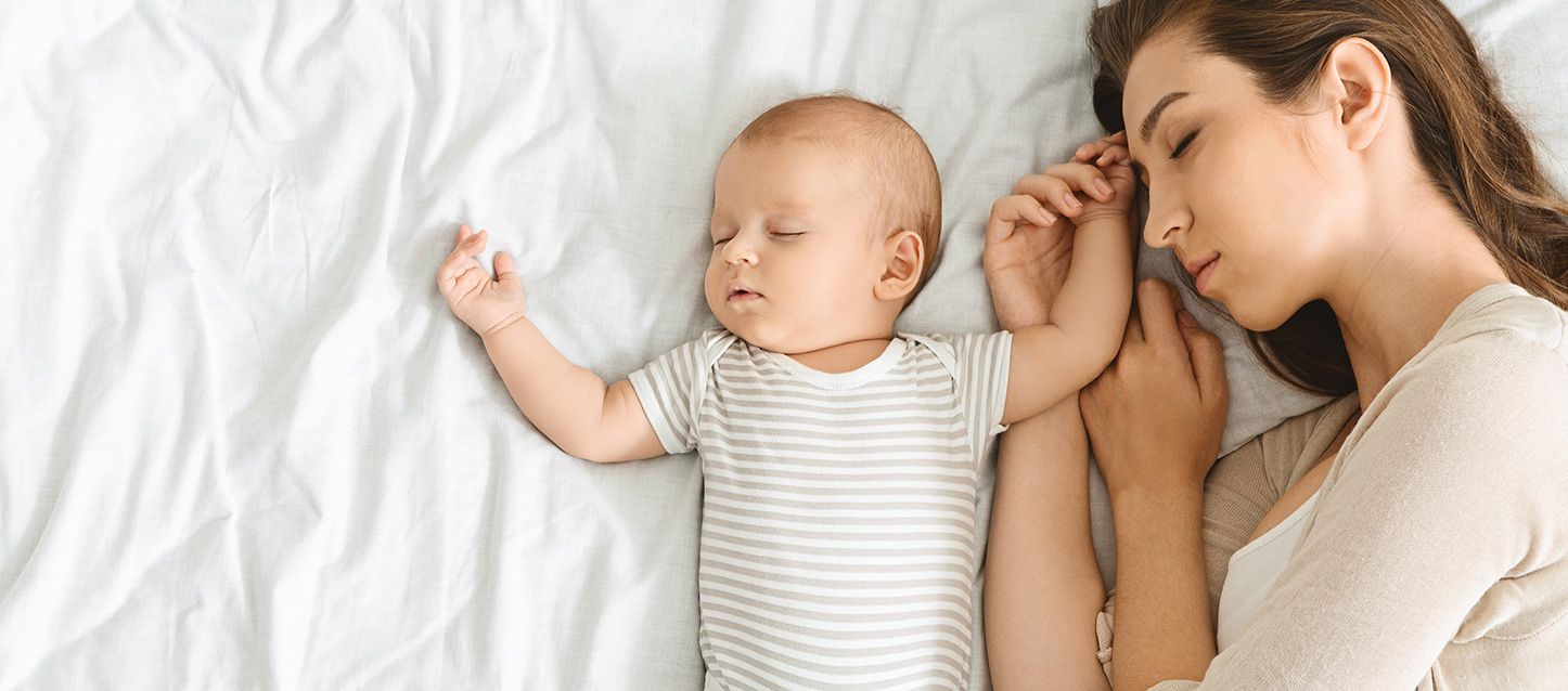 sueño fragmentado durante la maternidad madre durmiendo junto a su bebe en la cama