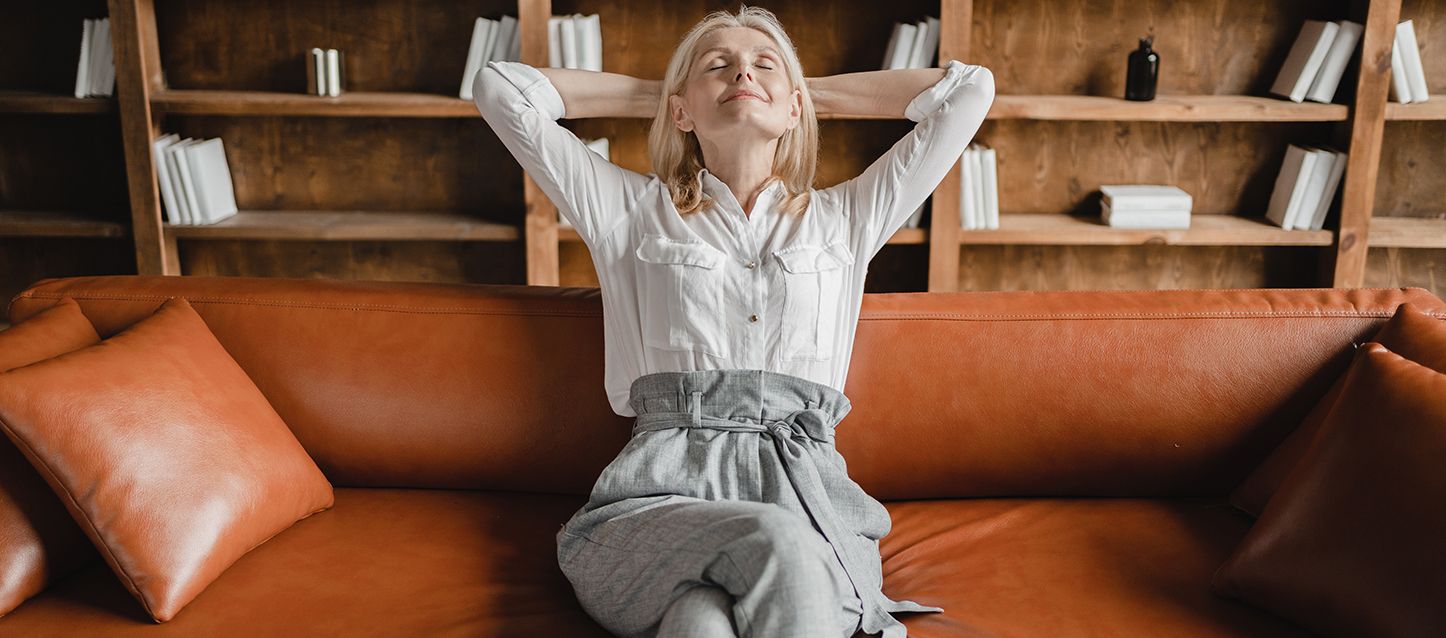 mujer rubia durmiendo la siesta sentada en un colchón marrón con cara de satisfacción