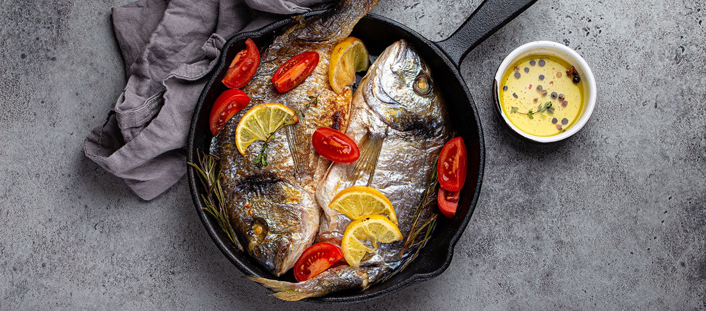 sartén con pescado y bol de aceite y un trapo