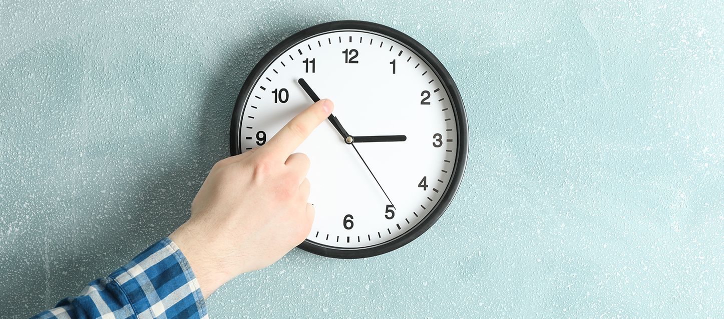 Reloj de pared marcando las 2:54 donde hay una mano tocando la manecilla de los minutos