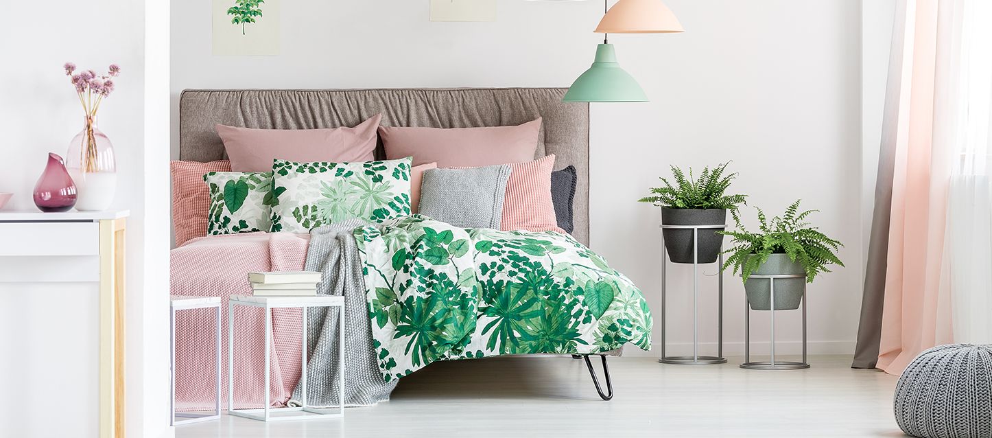 Orden del dormitorio Dormitorio con cama, edredón, cojines, 2 macetas y dos mesitas, una con libros