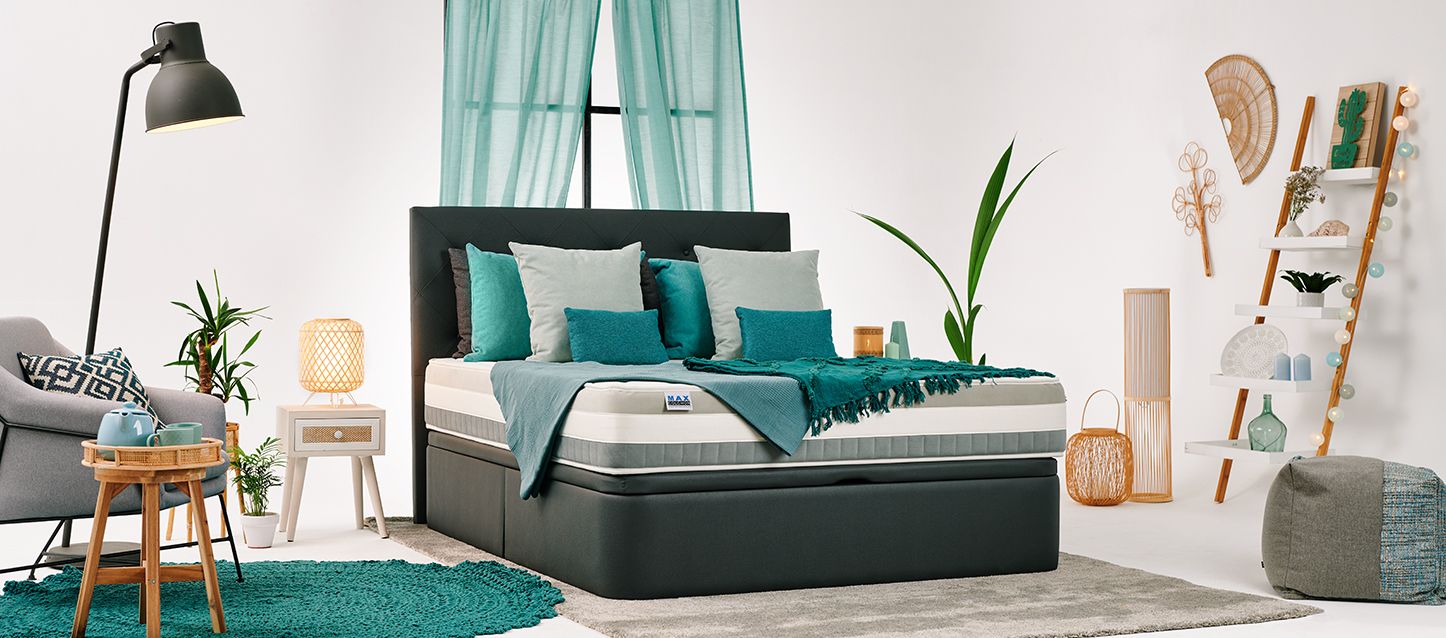 Potencia el confort Descubre los beneficios de los colchones firmes Habitación con soporte con colchón firme y cabecero, mesita de noche, sillónm puf, estanteria con objetos y ventana con cortina