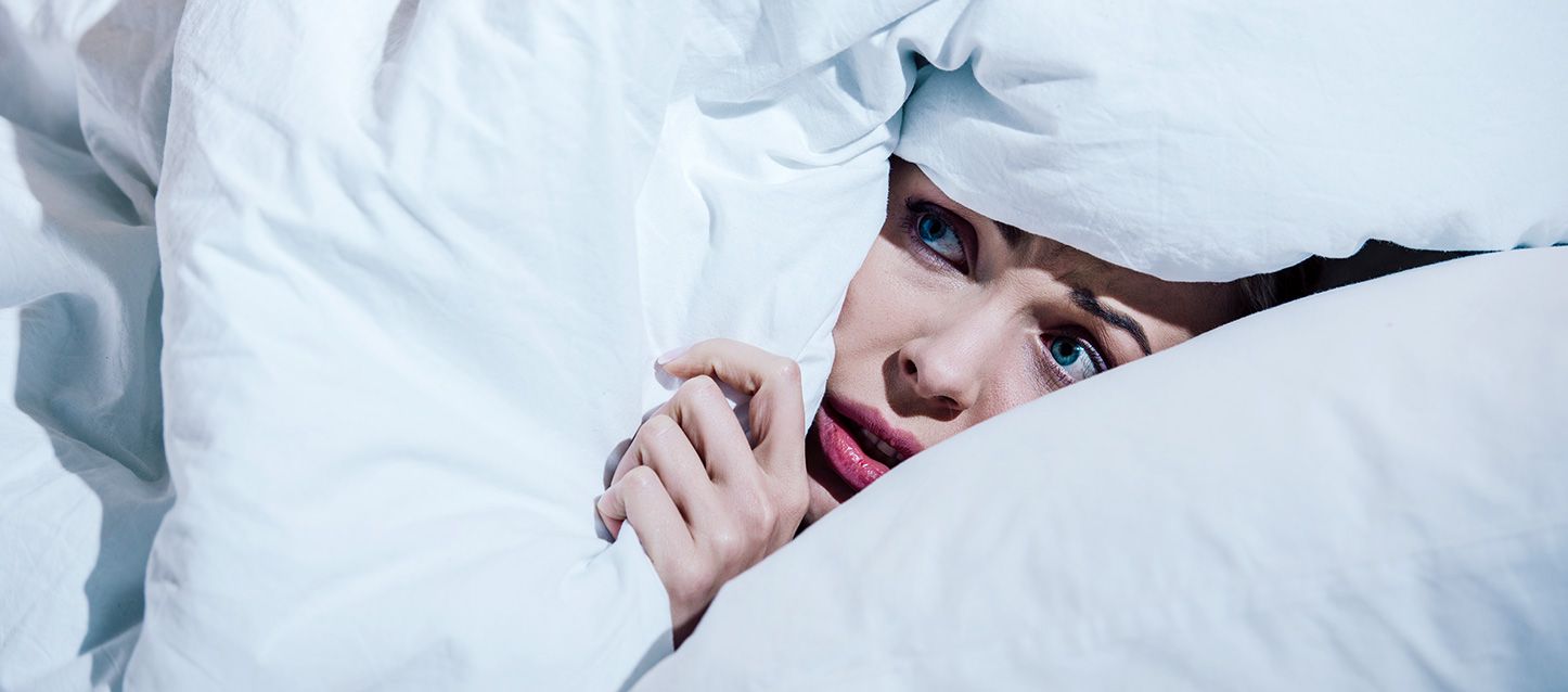 blog-1 chica de ojos azules tapada con el edredon hasta la cara con cara de miedo por soñar con sangre
