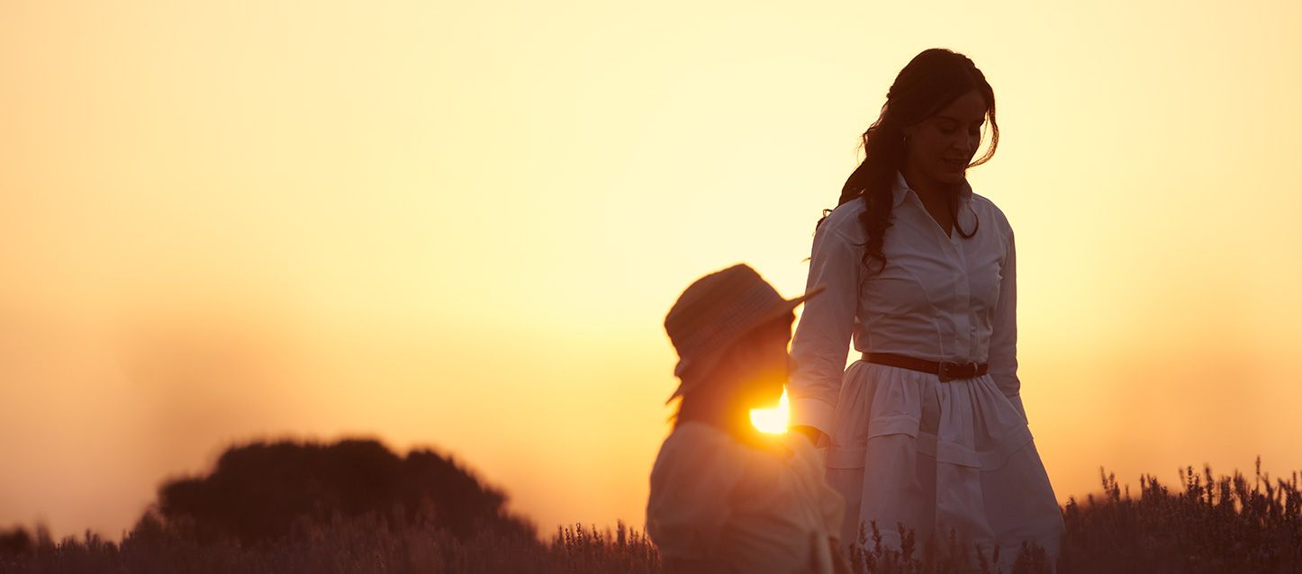 Una mujer y su hija caminando por el campo al atardecer