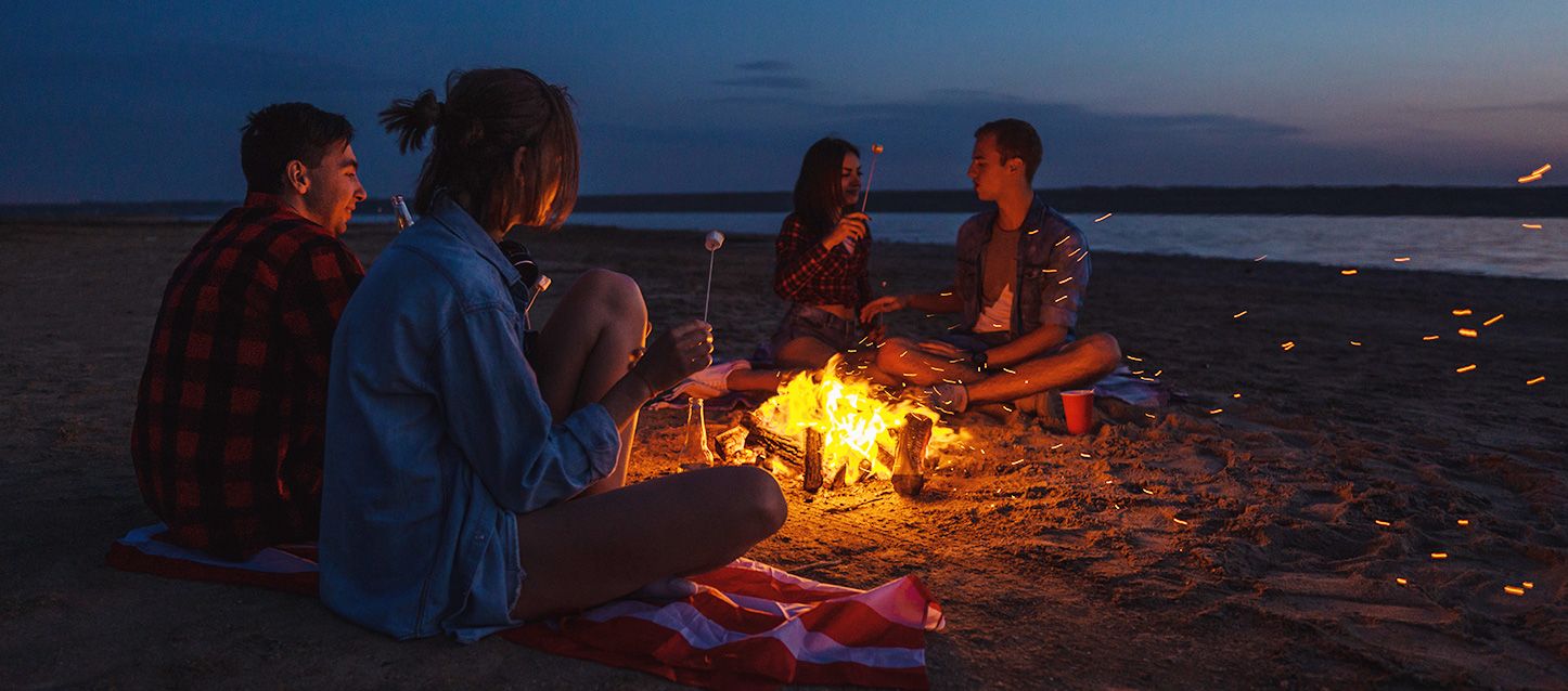 La leyenda de la noche de San Juan 4 amigos sentados en la playa alrededor de una hoguera en la noche de San Juan